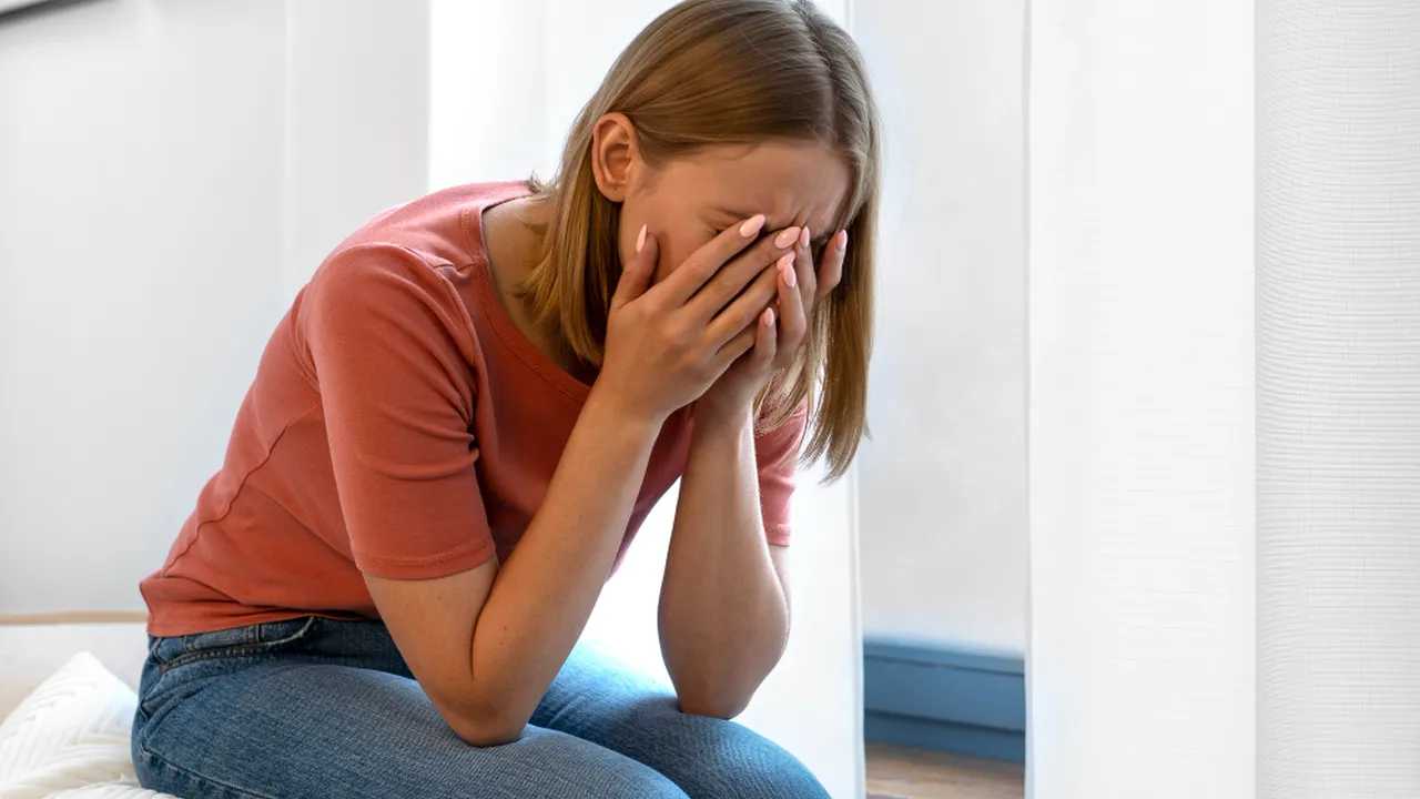 Mujer con ansiedad, cubriendo su rostro con las manos en casa.