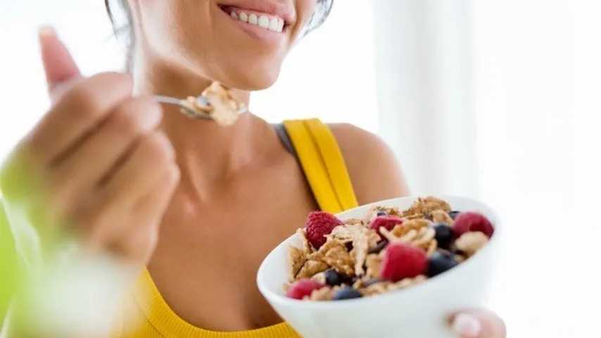 Mujer jóven comiendo después de practicar deporte. (Foto: Freepik)