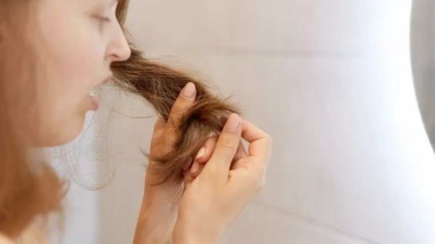 Mujer sorprendida mirando su pelo. (Foto: Freepik)