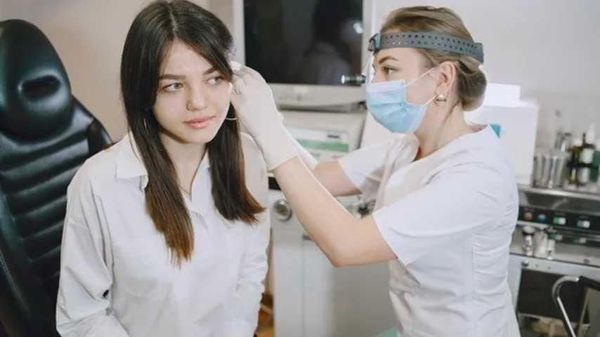 Una mujer médico especialista en otorrinolaringología explorando el oído. (Foto: Freepik)